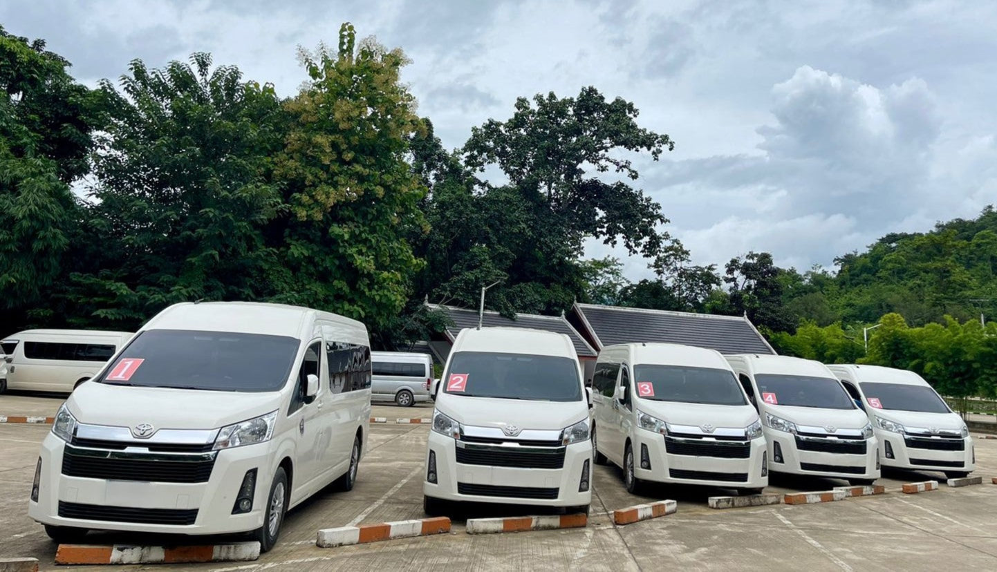 Row of white vans parked in a lot with trees in the background