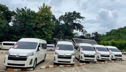 Row of white vans parked in a lot with trees in the background